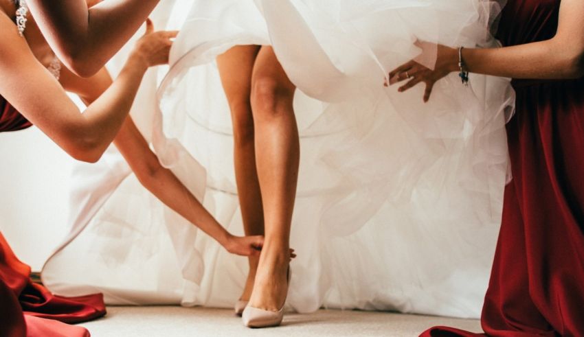 A group of bridesmaids putting on a bride's dress.