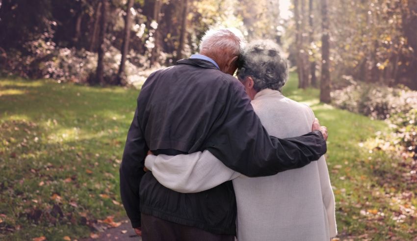 An elderly couple walking in the woods.