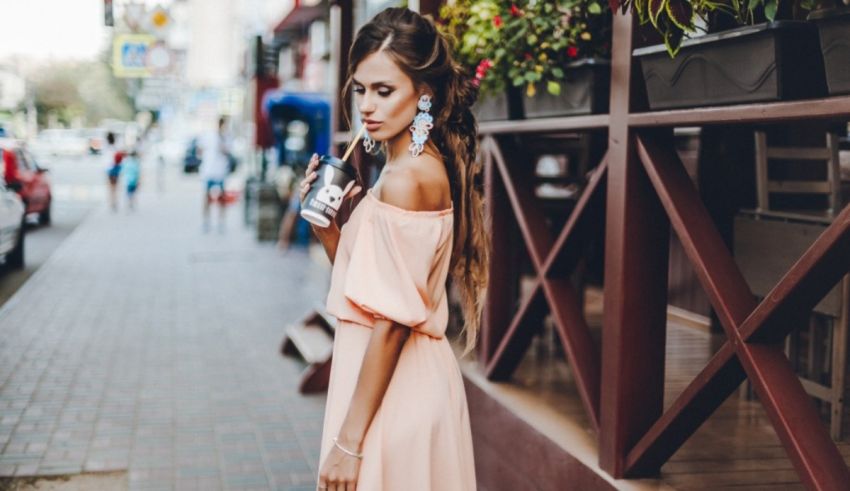 A woman in a pink dress standing on a sidewalk.