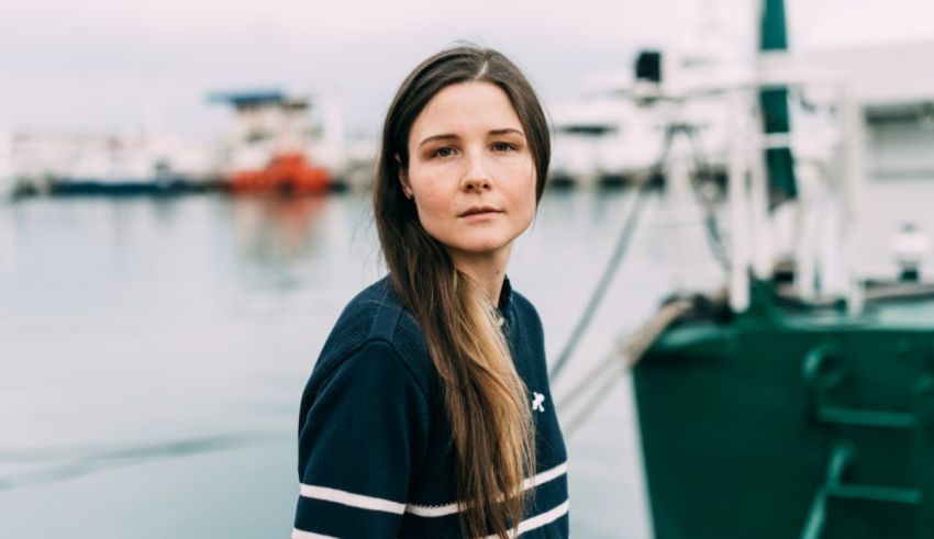 A woman with long hair standing in front of a boat.
