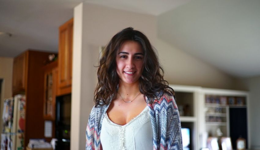 A young woman smiles while standing in a kitchen.