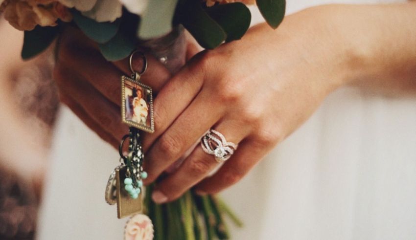 A bride holding her wedding ring and a bouquet of flowers.