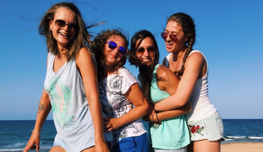 A group of girls on a beach posing for a picture.