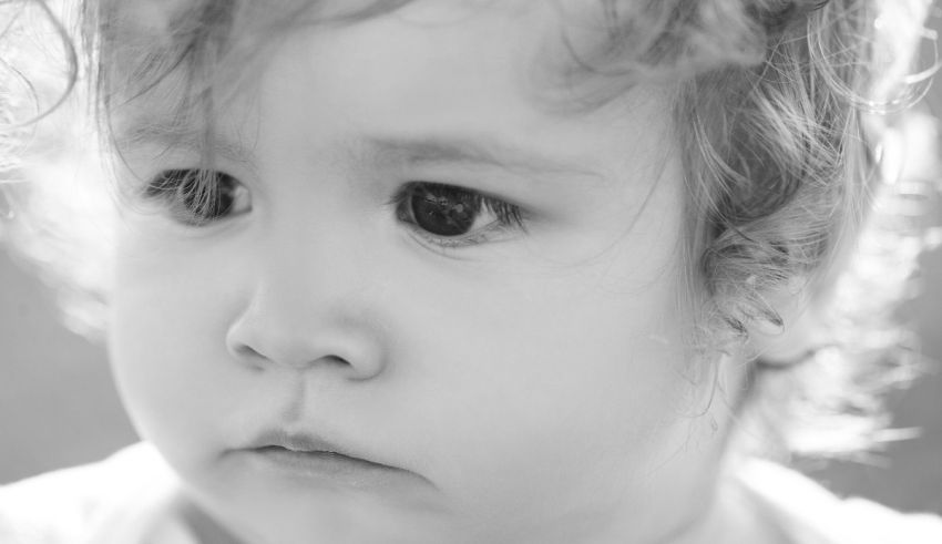 A black and white photo of a child with curly hair.