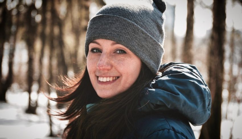 A woman wearing a beanie in the woods.