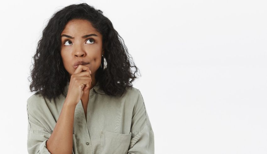A young black woman thinking with her hand on her chin.