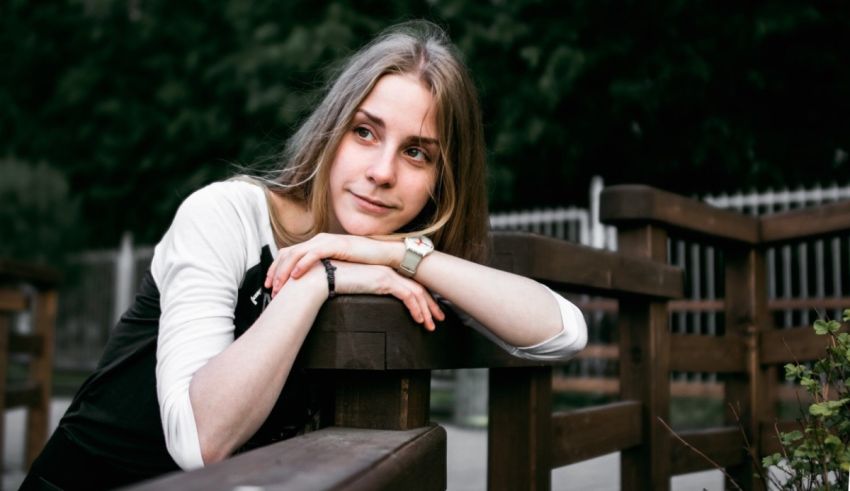 A young woman leaning on a wooden fence.