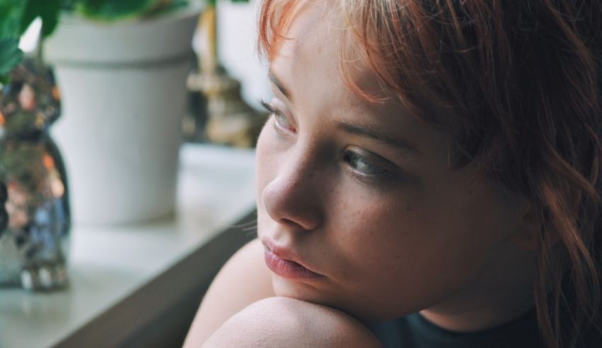 A girl with red hair looking out a window.