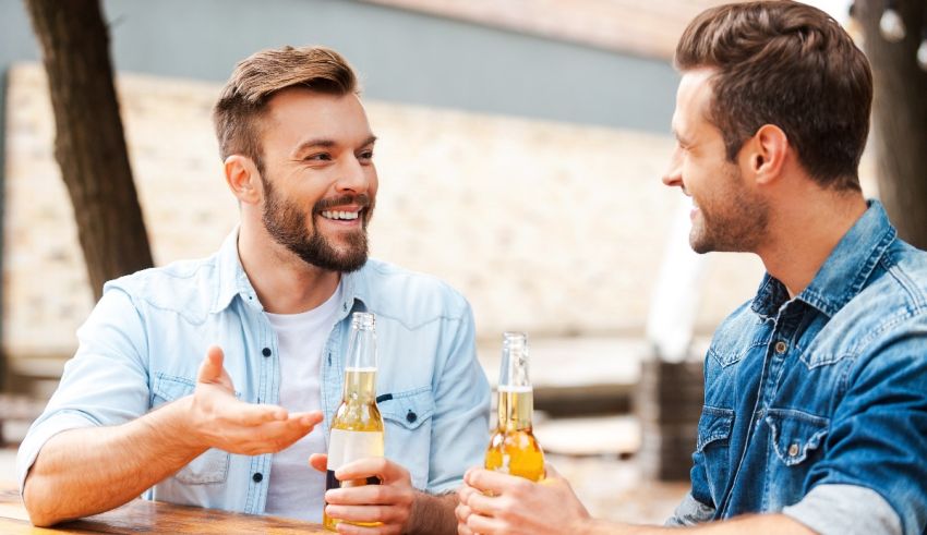 Two men drinking beer at an outdoor table.