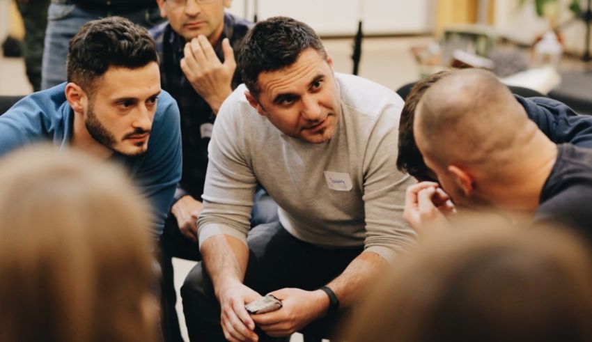 A group of people in a circle looking at a cell phone.
