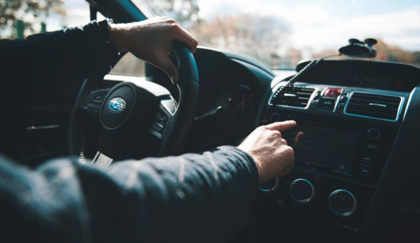 A man is driving a car with his hands on the steering wheel.
