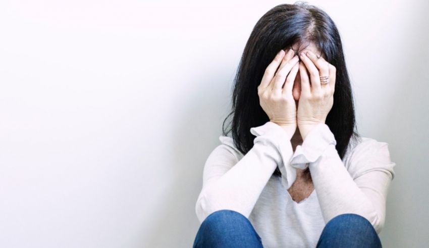 A woman covering her face with her hands.
