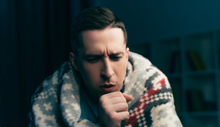 A man with a cold wrapped in a blanket.
