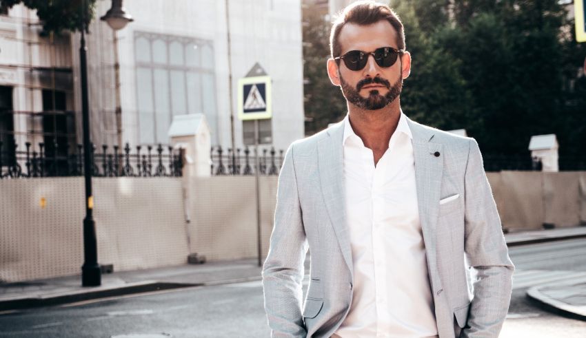 A man in a suit and sunglasses standing on a street.