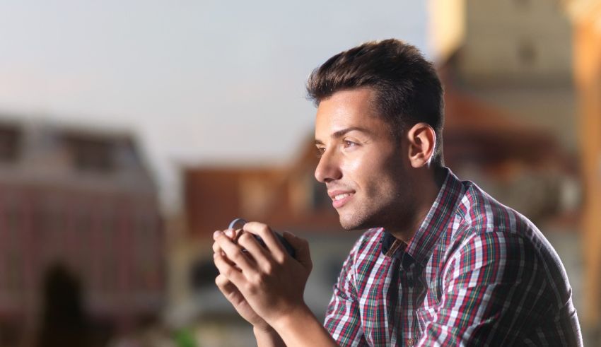 A young man is looking at his phone while sitting on a bench.