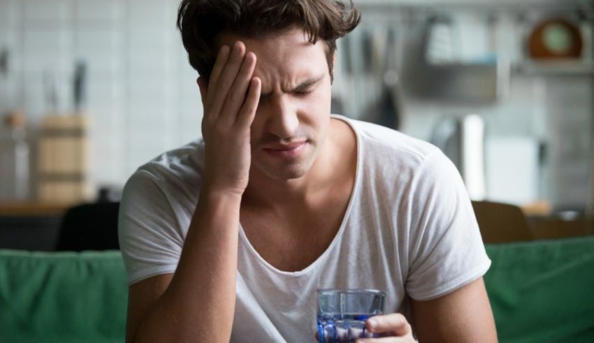 A man with a headache holding a glass of water.