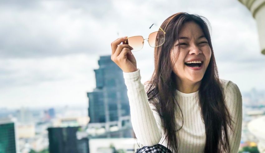 A young asian woman is laughing while sitting on top of a building.