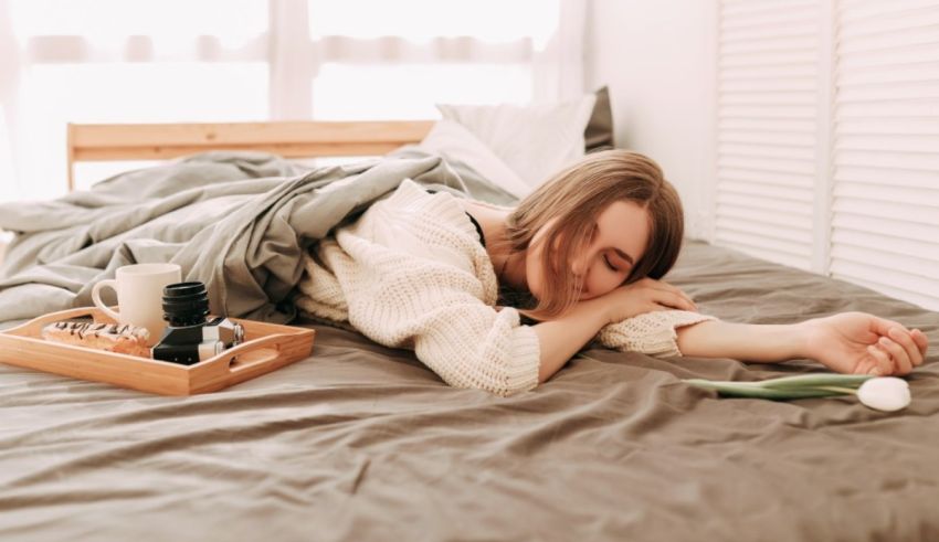 A woman is sleeping on a bed with a tray in front of her.