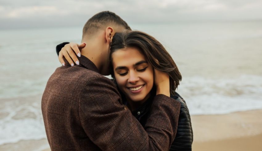 A man and woman hugging on the beach.