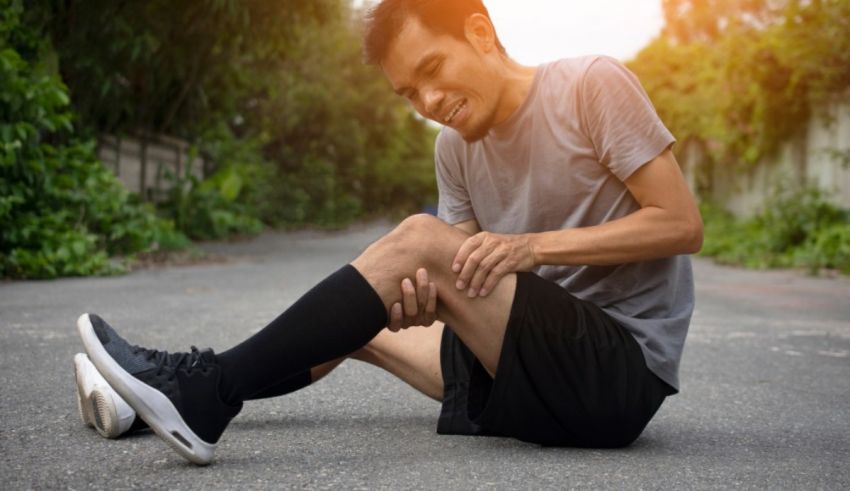 A man sitting on the road with a knee injury.