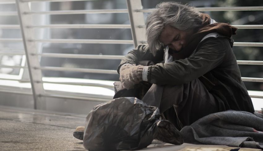 A homeless man sitting on the ground.