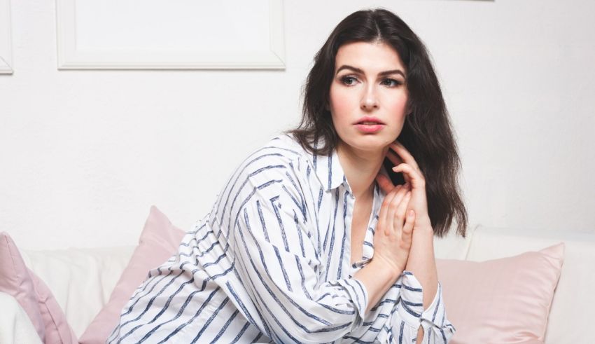 A woman in a striped shirt sitting on a couch.