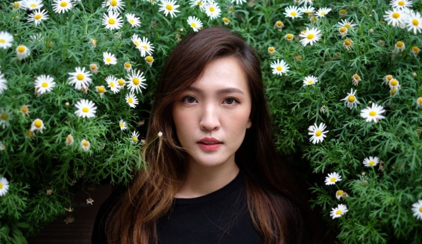 A woman posing in a field of daisies.
