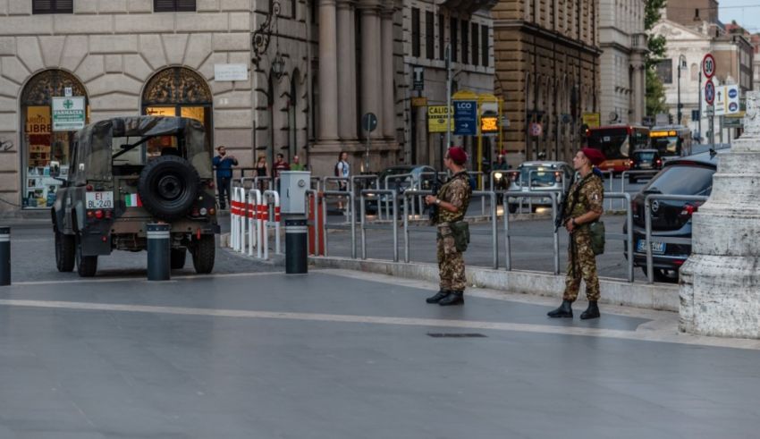 Two soldiers standing in front of a car on a city street.