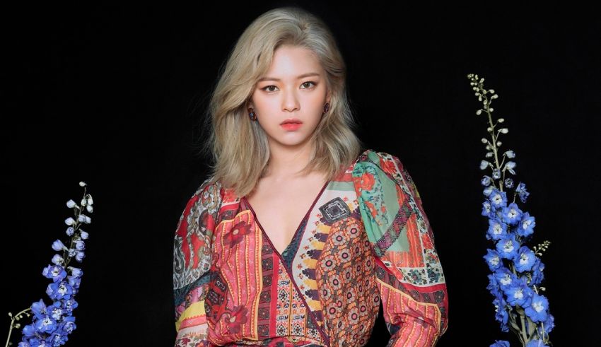 A woman in a colorful dress posing in front of flowers.