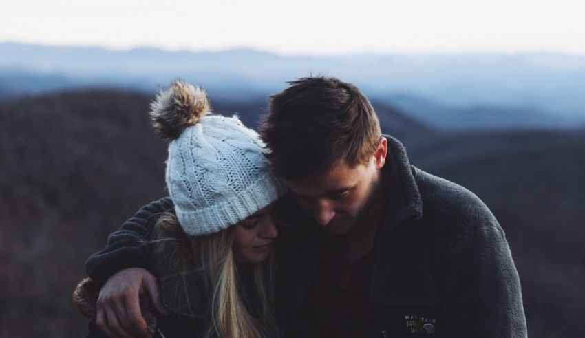 A man and woman hugging on top of a mountain.
