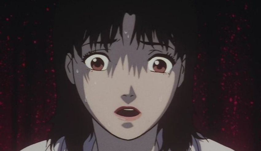 A woman in a white shirt is staring at a red light.