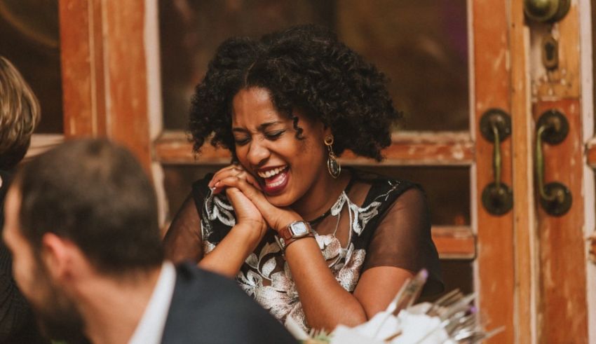 A woman laughs while sitting at a table.