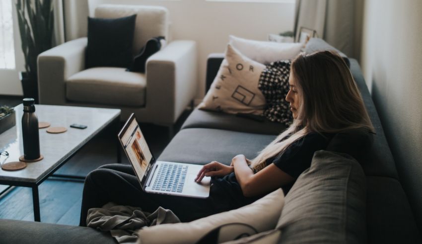 A woman sitting on a couch using a laptop.