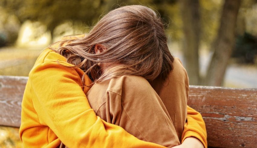 A girl is sitting on a bench with her hands on her head.
