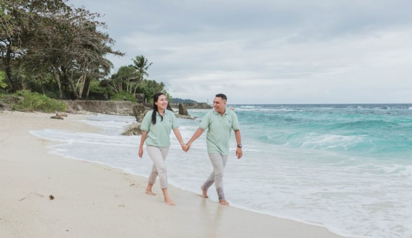 A couple walking on the beach holding hands.