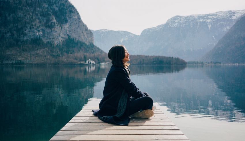 A woman sitting on a dock in a mountain lake.