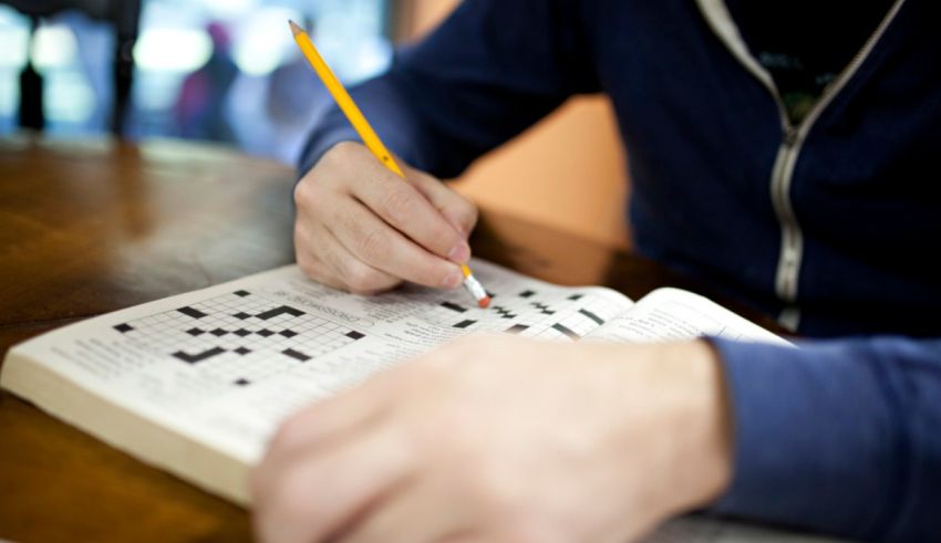 A man is writing on a crossword puzzle.