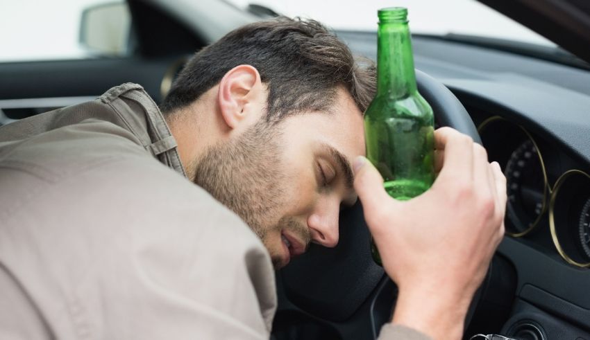 A man in a car with a beer bottle on his head.