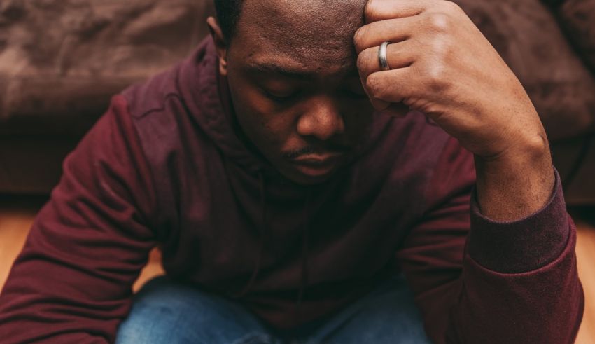 A man sitting on the floor with his hand on his head.