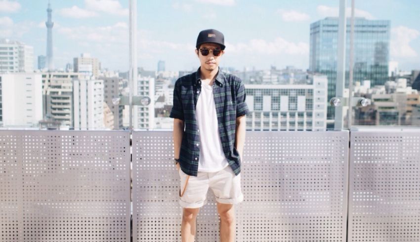 A young man standing on a balcony with a view of the city.
