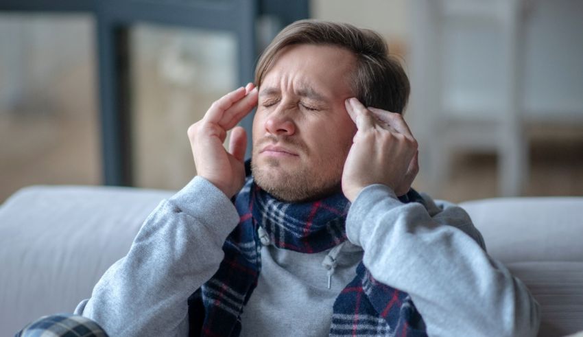 A man sitting on a couch with his hands on his head.