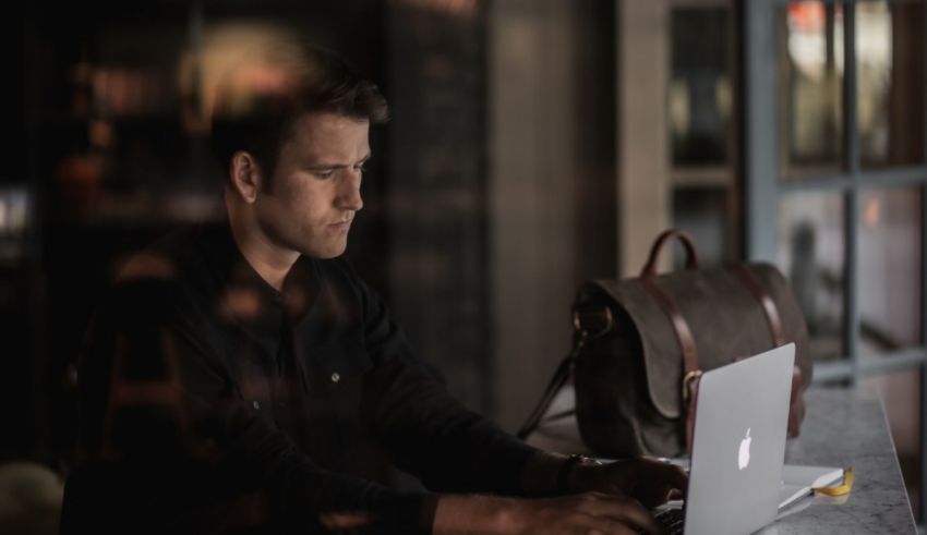 A man sitting at a table using a laptop.