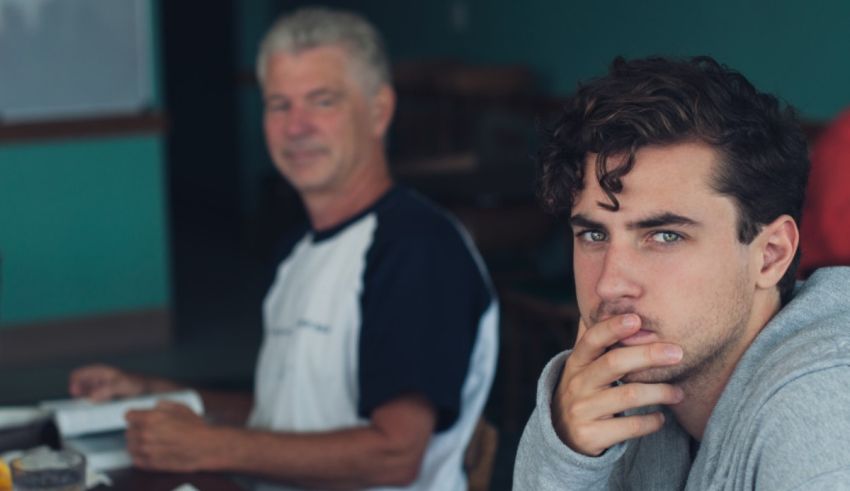 A young man is sitting at a table with an older man.