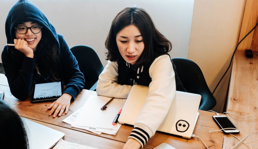 A group of women sitting around a table with laptops.