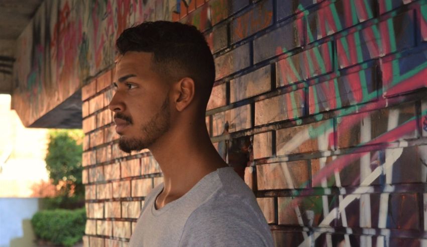 A man standing against a brick wall.