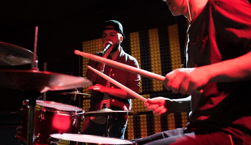 Two men playing drums in a recording studio.