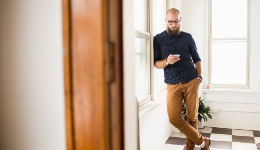 A man standing in front of a door looking at his phone.