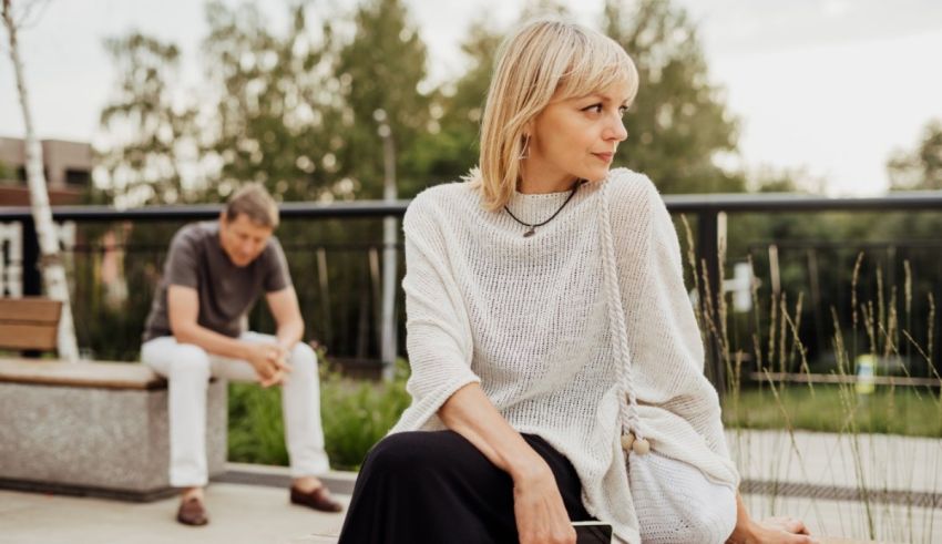 A man and woman sitting on a bench in a park.