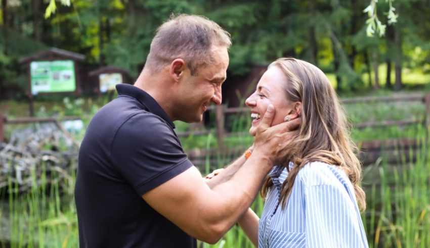 A man and woman hugging in front of a pond.