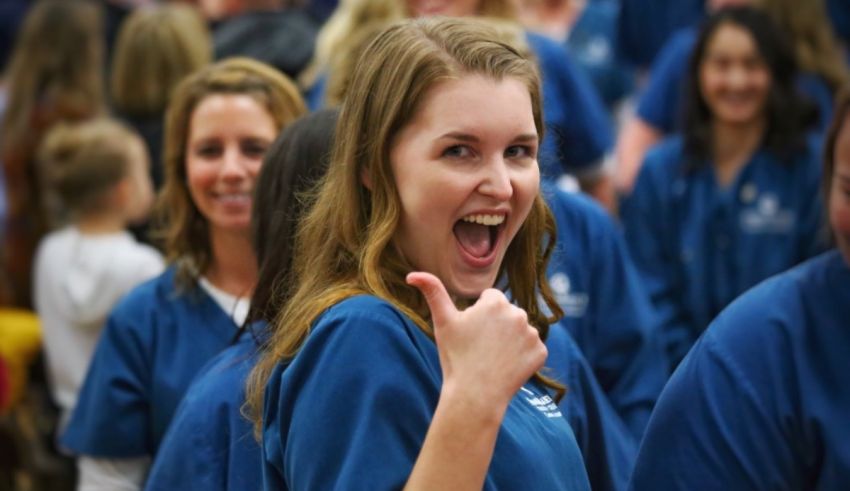 A woman is giving the thumbs up in front of a group of people.